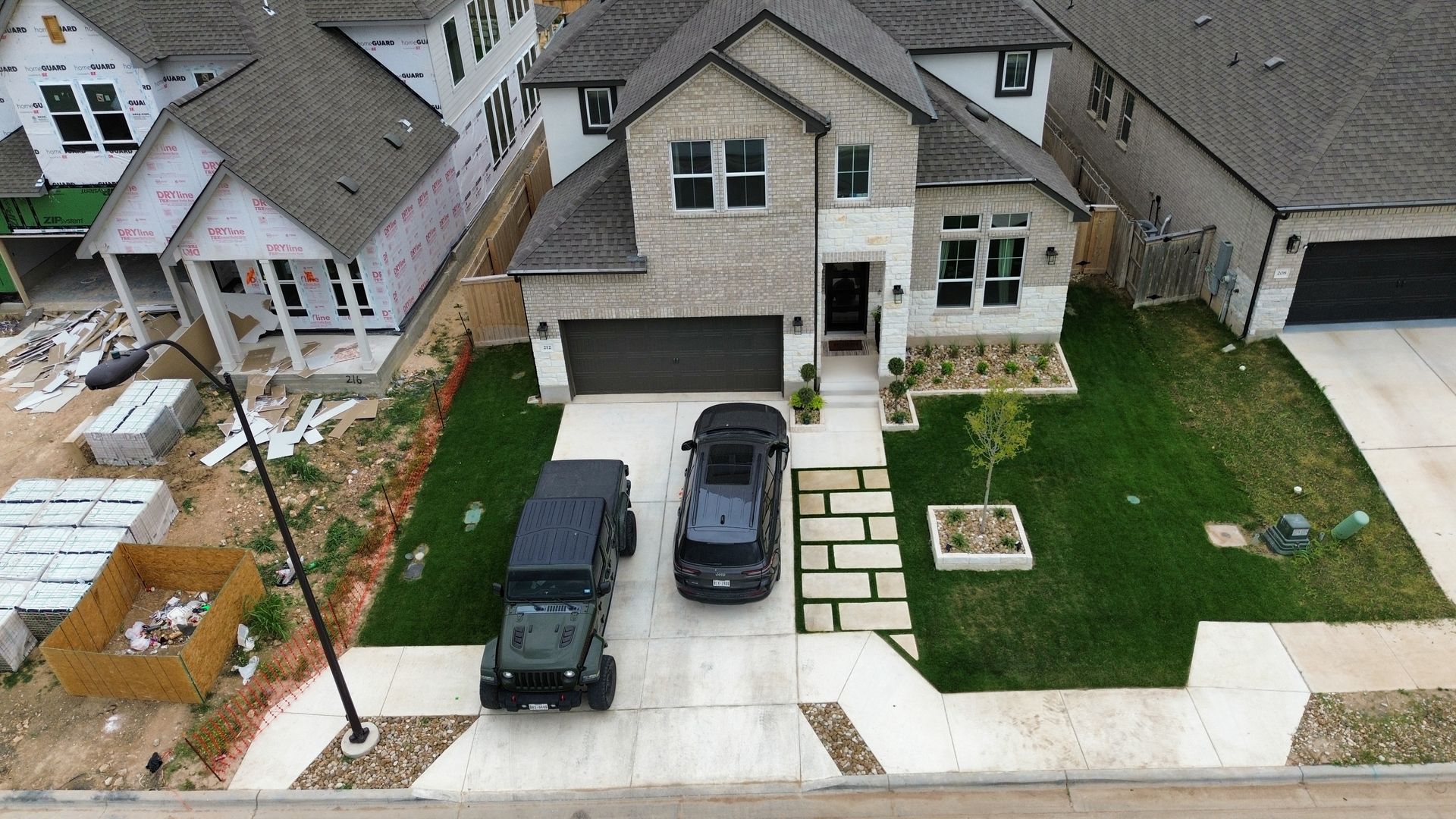 An aerial view of a house with two cars parked in front of it.