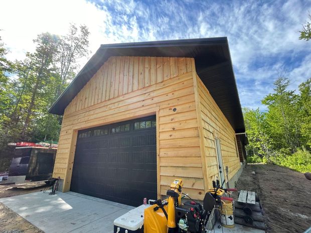 Two construction workers are standing in front of a wooden house under construction.