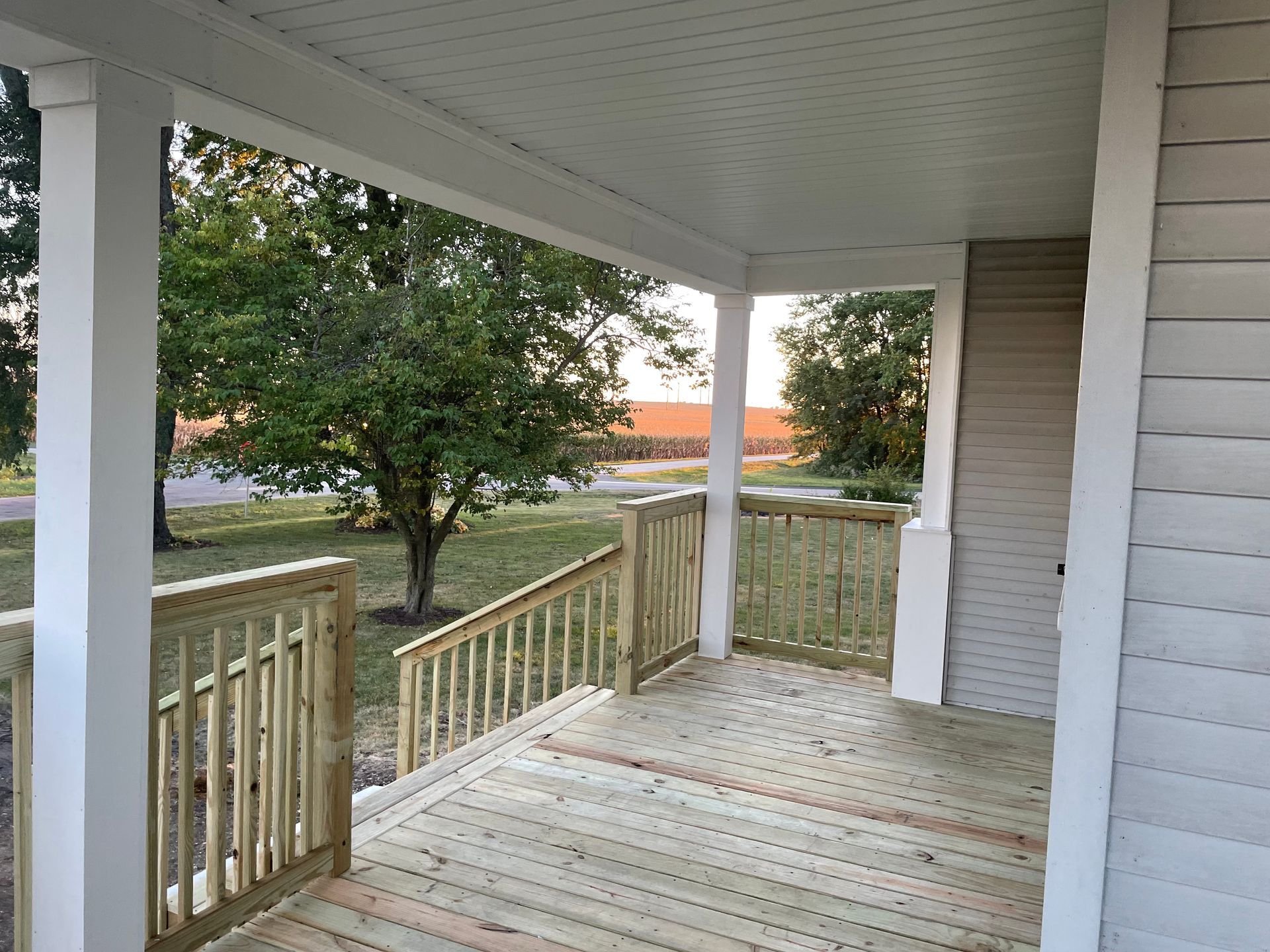 A wooden deck with chairs and umbrellas on it overlooking a body of water.