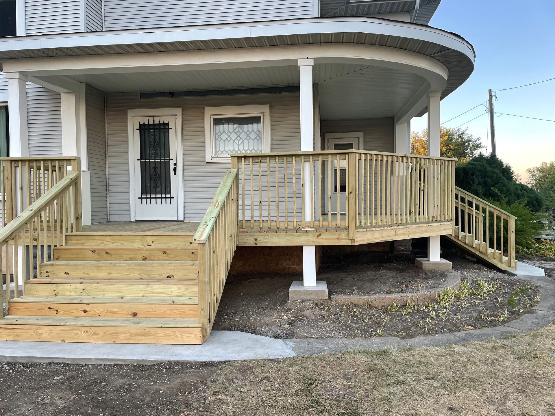 A white house with a large wooden deck in front of it