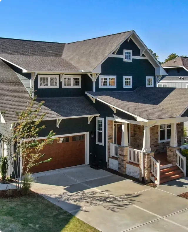 A large green house with a brown garage door