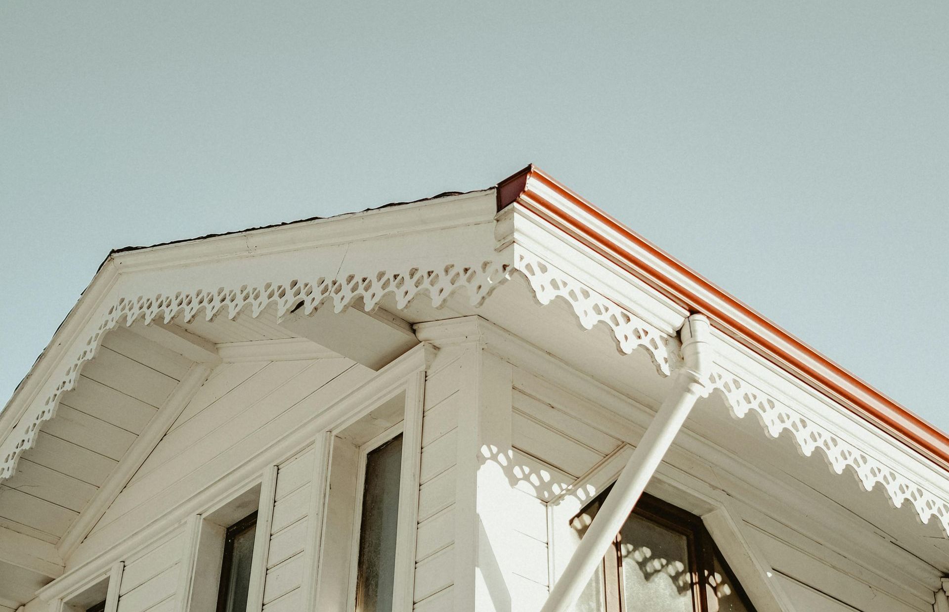 The roof of a white house with a red gutter