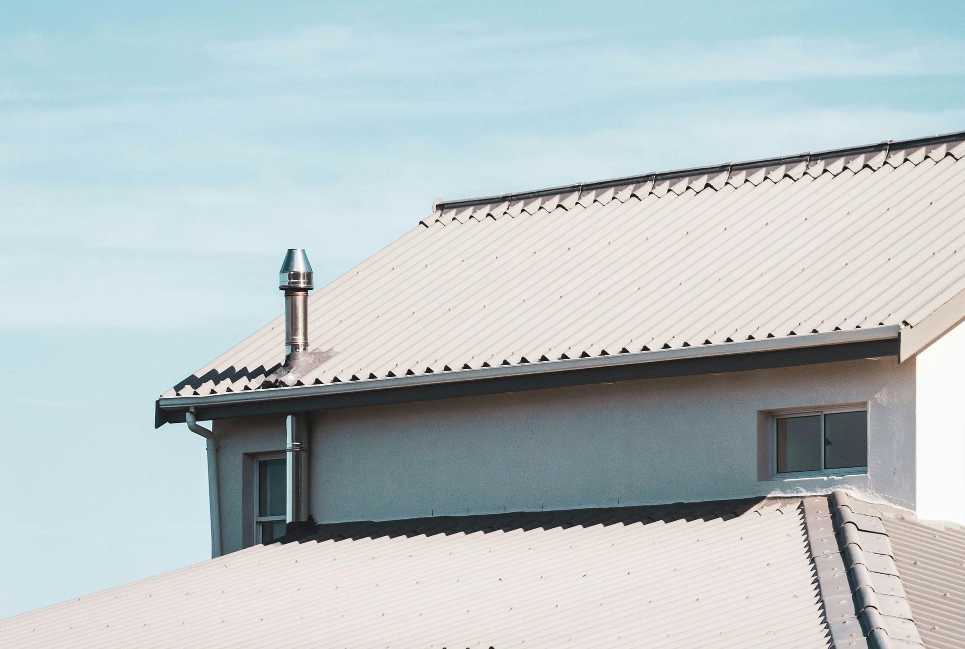 A white house with a white roof and a chimney on top of it.