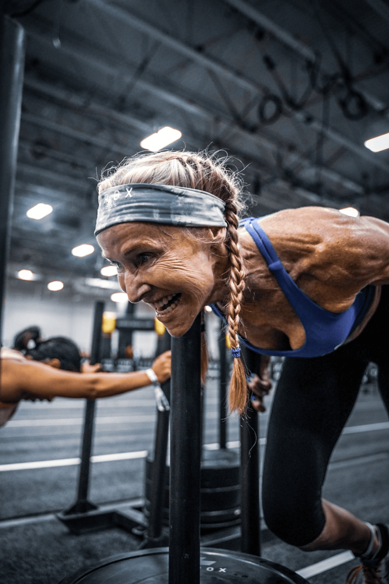 A woman is pushing a sled in a gym.