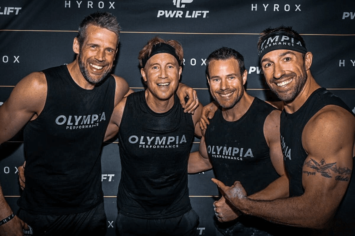 A group of four men are posing for a picture after a HYROX competition with Olympia Performance