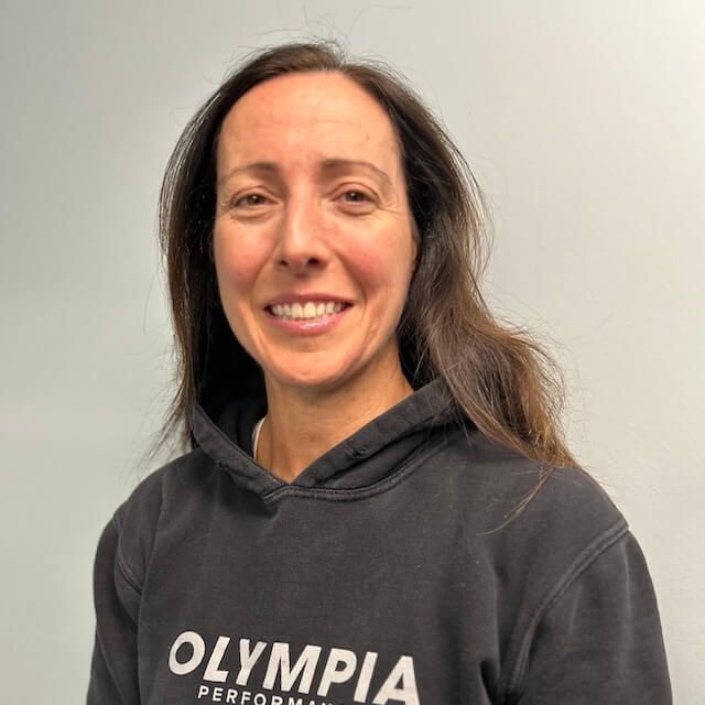 Karen Cutler wearing a black Olympia sweatshirt is smiling for the camera.
