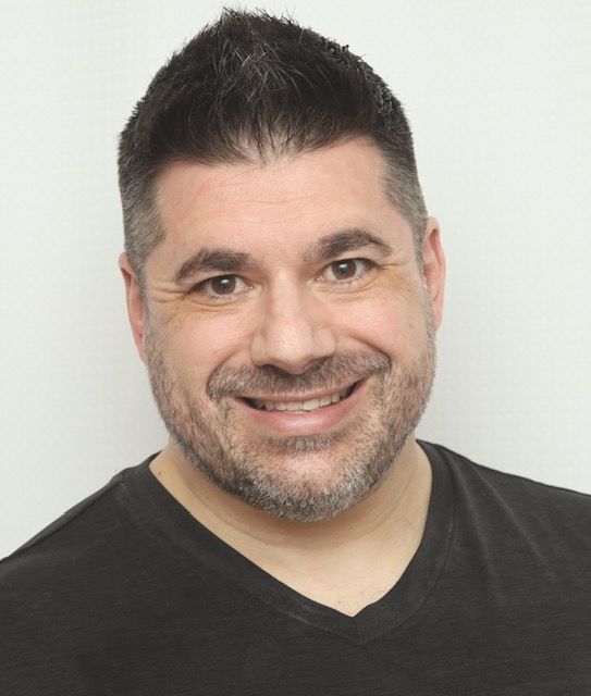 A man with a beard is smiling and wearing a black shirt