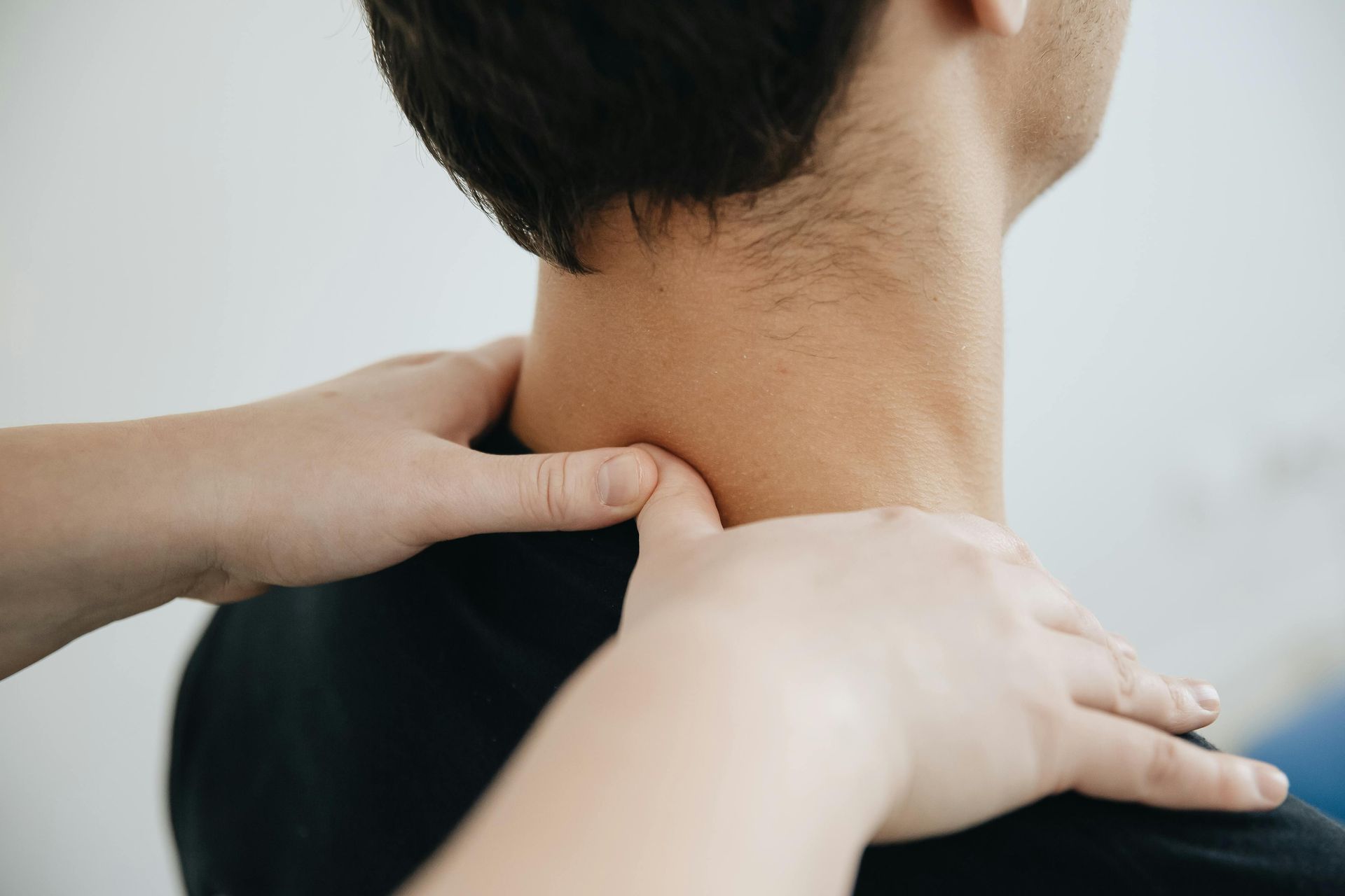 A person receives a massage on their neck and shoulders from another individual.