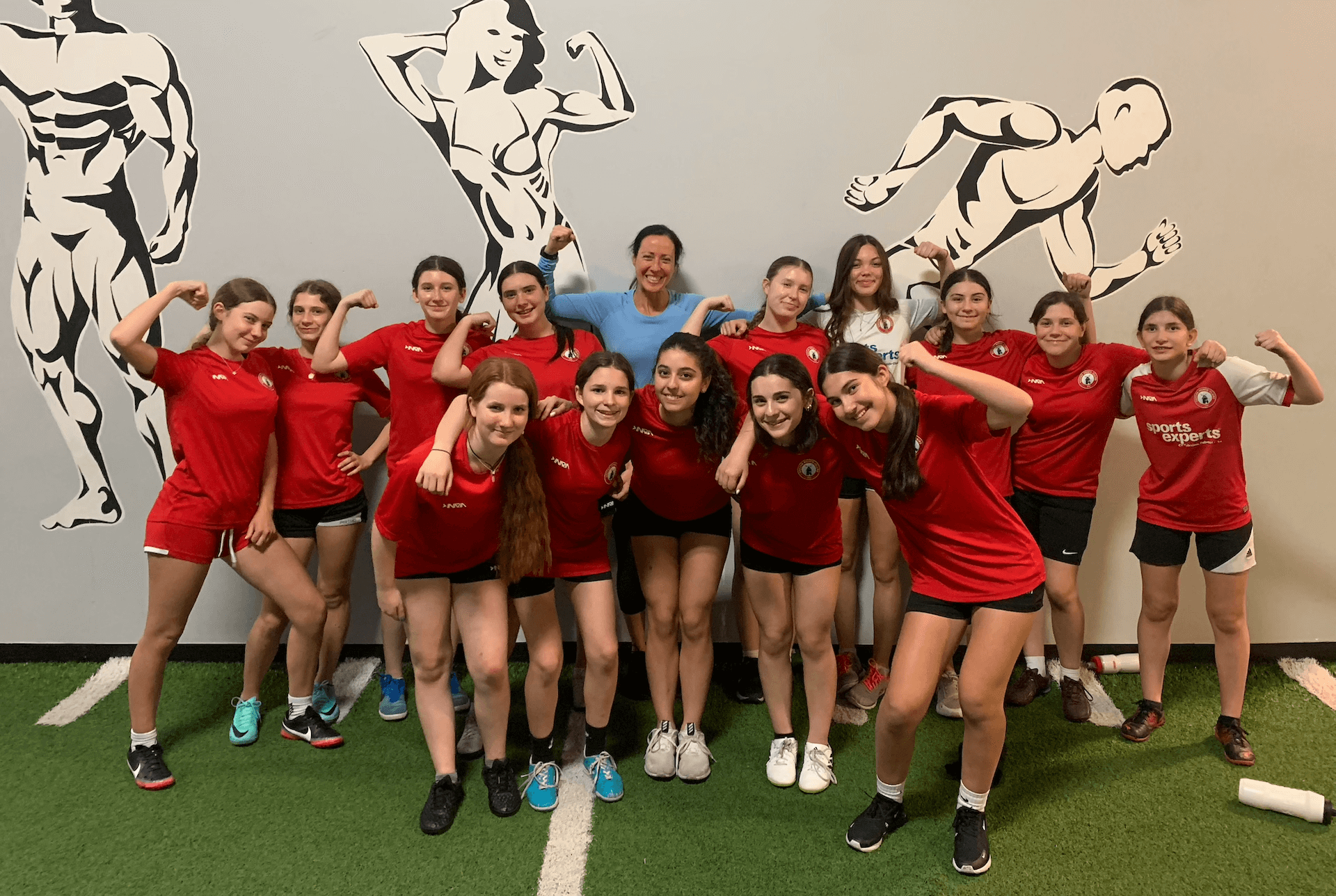 A group of young girls from a youth sports team are posing for a picture in a gym.