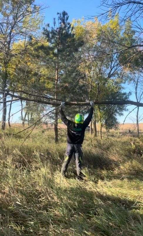 A man is carrying a large tree branch in a field.