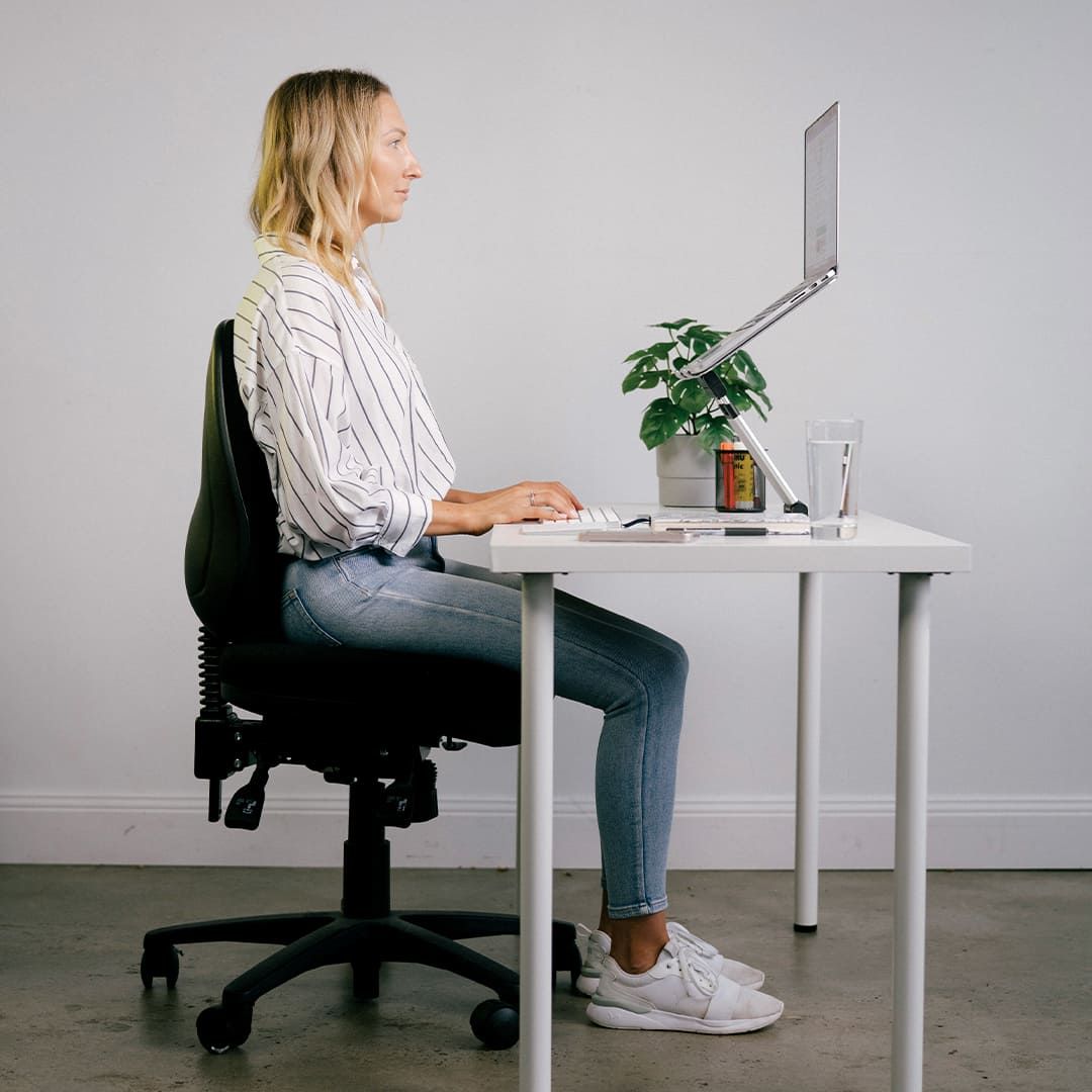 A Woman Is Sitting At A Desk In Front Of A Computer — Sea & Sand Chiropractic In Toukley, NSW