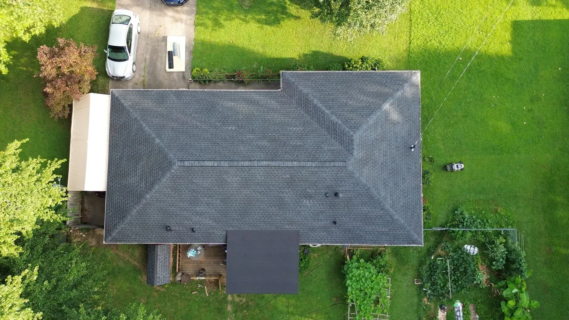 An aerial view of a house with a roof and a car parked in the driveway.