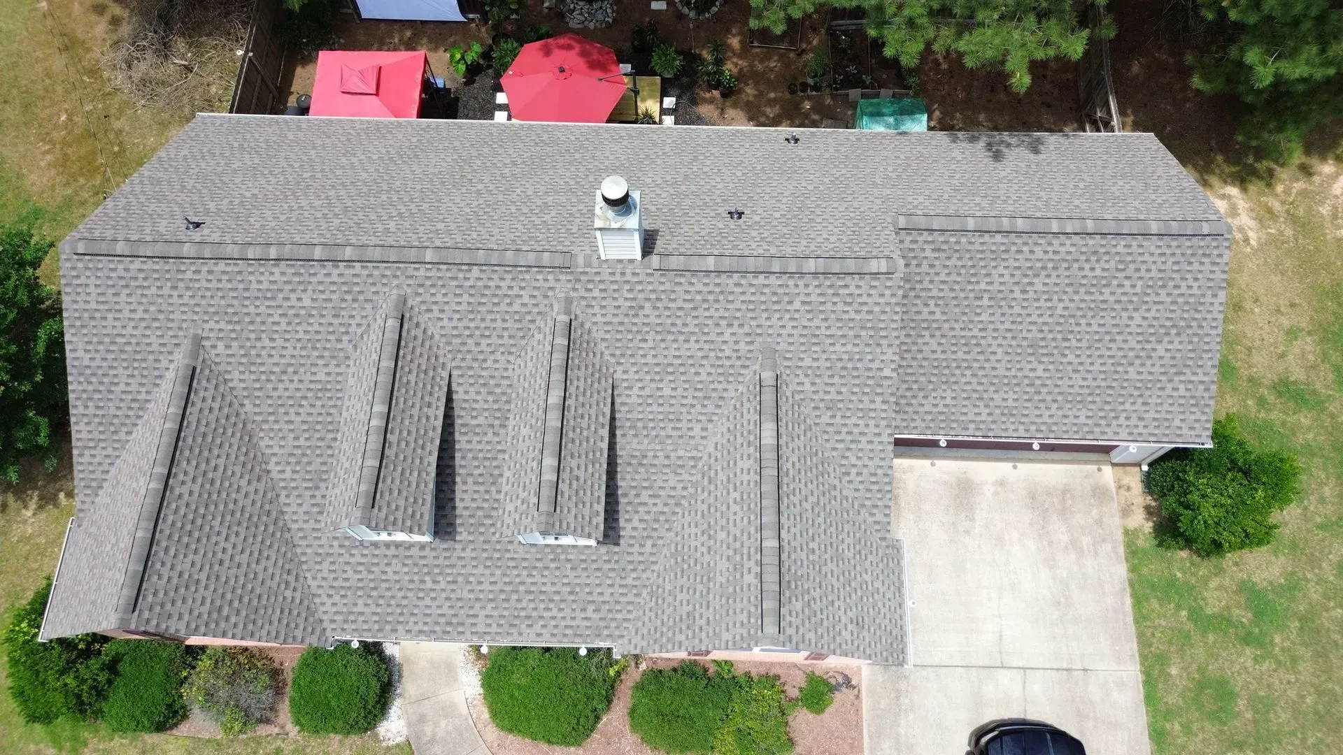 An aerial view of a house with a roof and a car parked in front of it.