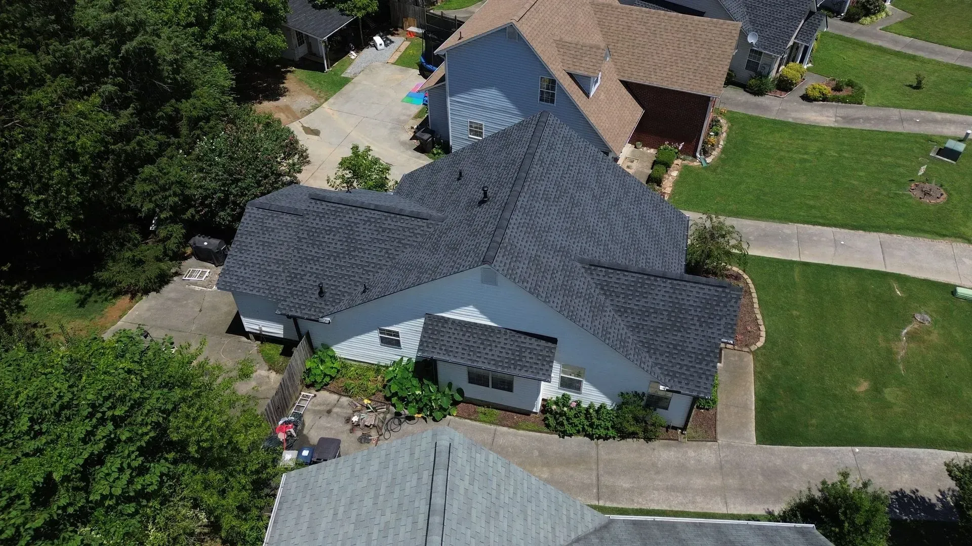 An aerial view of a house with a gray roof in a residential area.