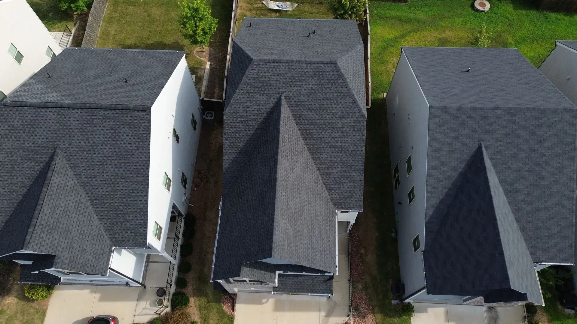 An aerial view of three houses with black roofs