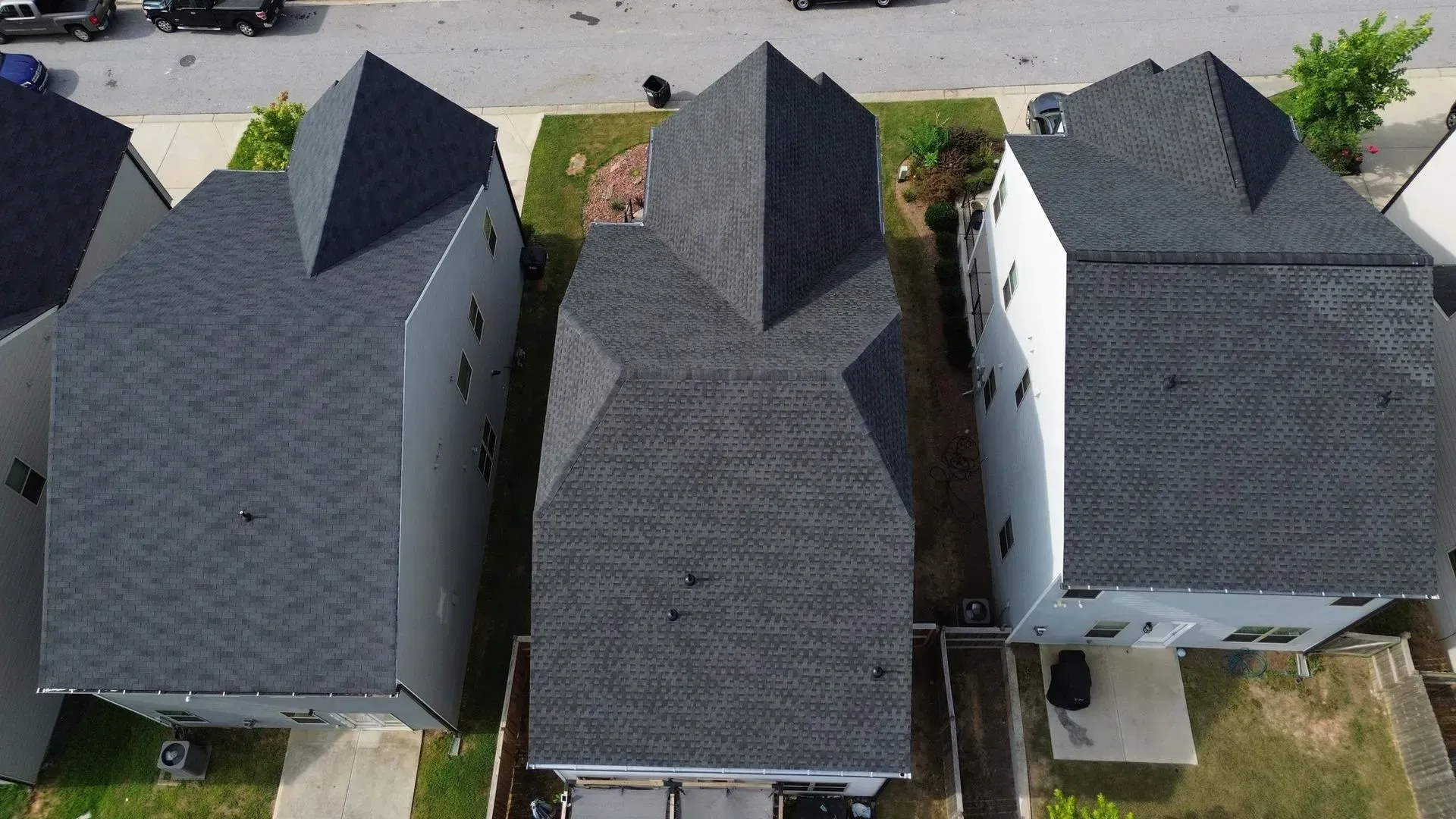 An aerial view of three houses with black roofs