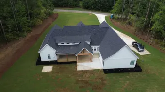 An aerial view of a large white house with a car parked in front of it.