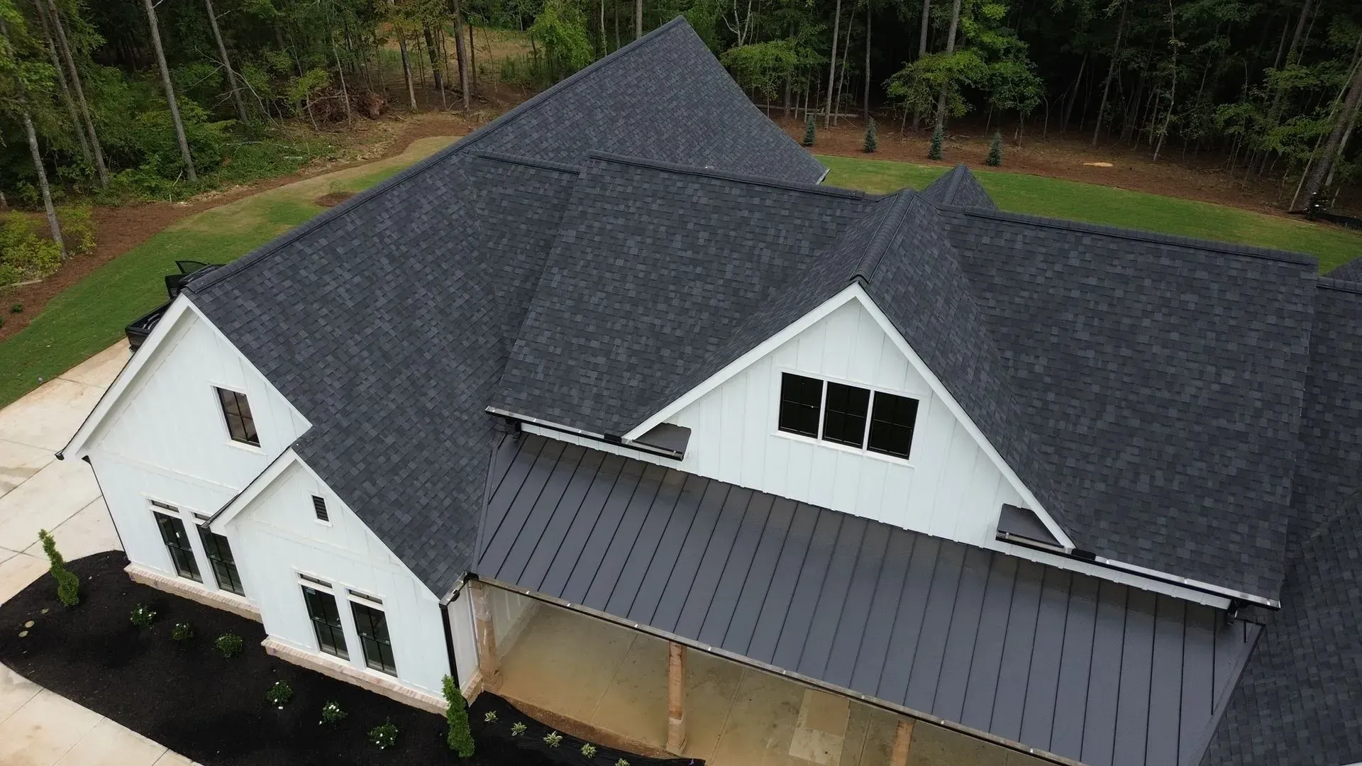 An aerial view of a large white house with a black roof.