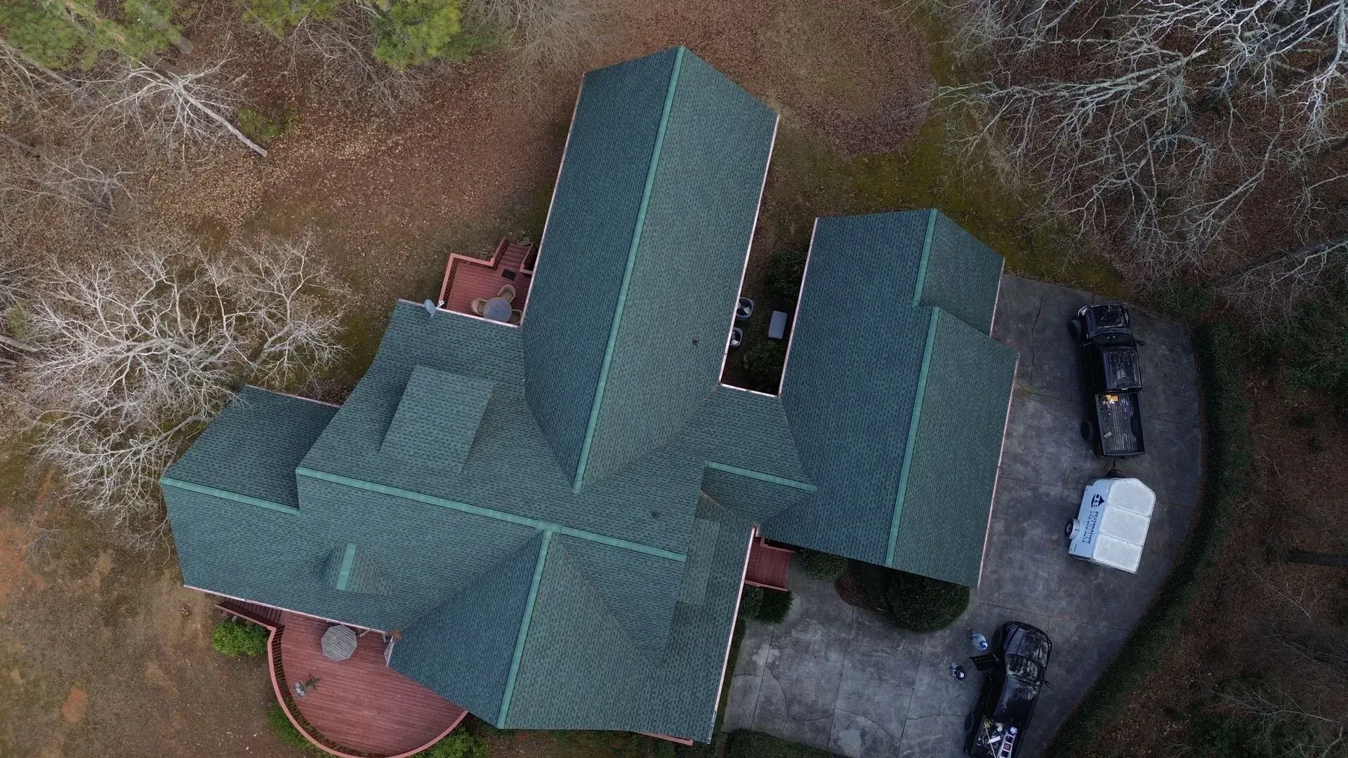 An aerial view of a house with a green roof and a car parked in front of it.