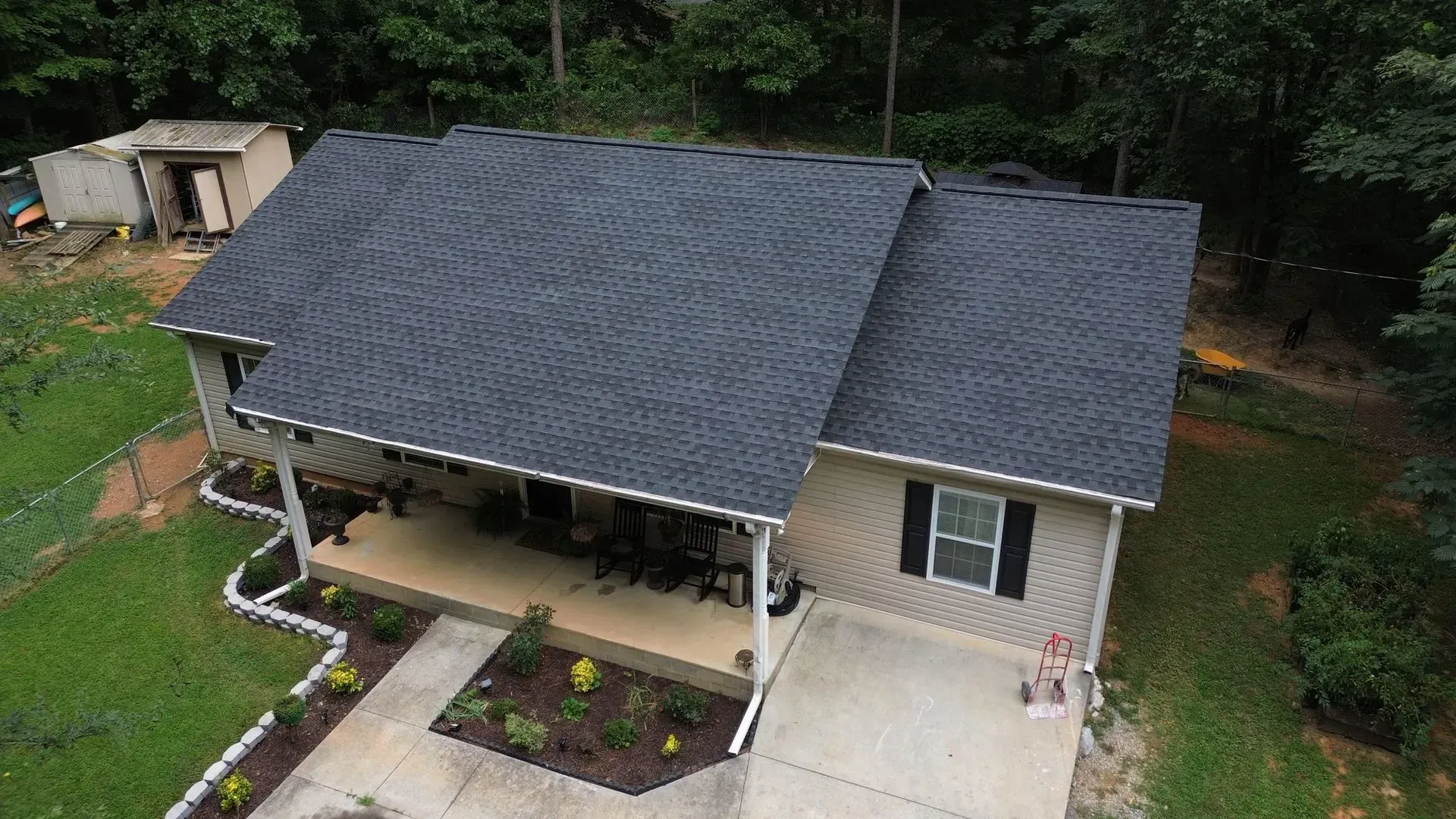 An aerial view of a house with a black roof and a porch.