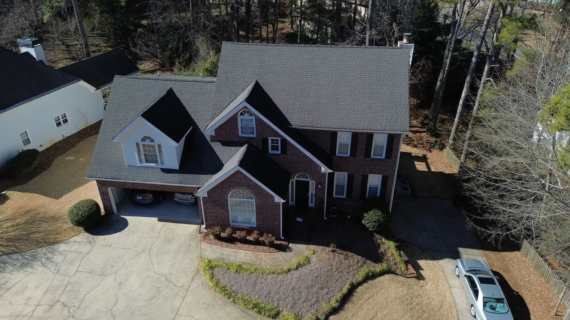 An aerial view of a large brick house with a car parked in front of it.