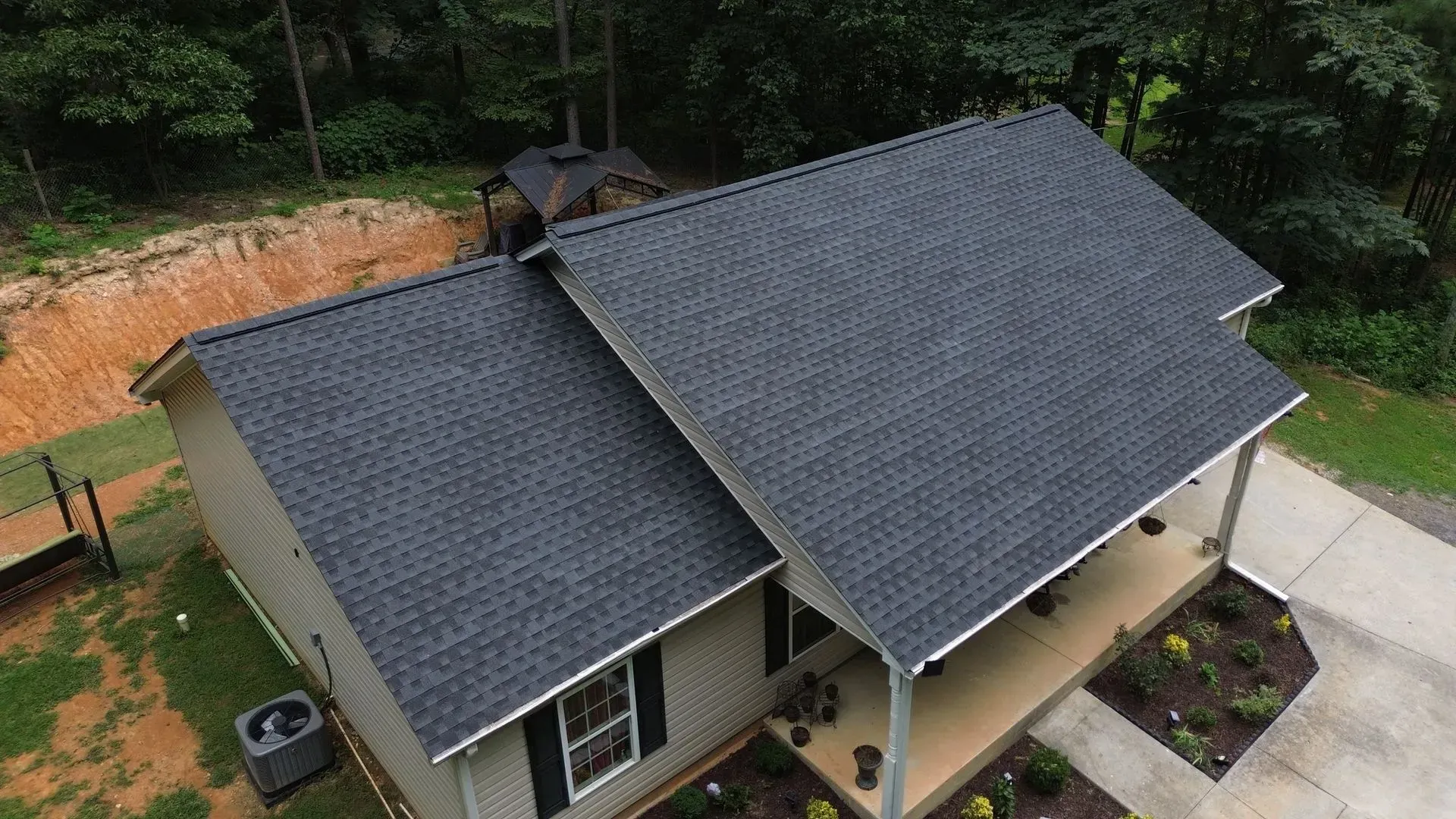 An aerial view of a house with a black roof and a porch.