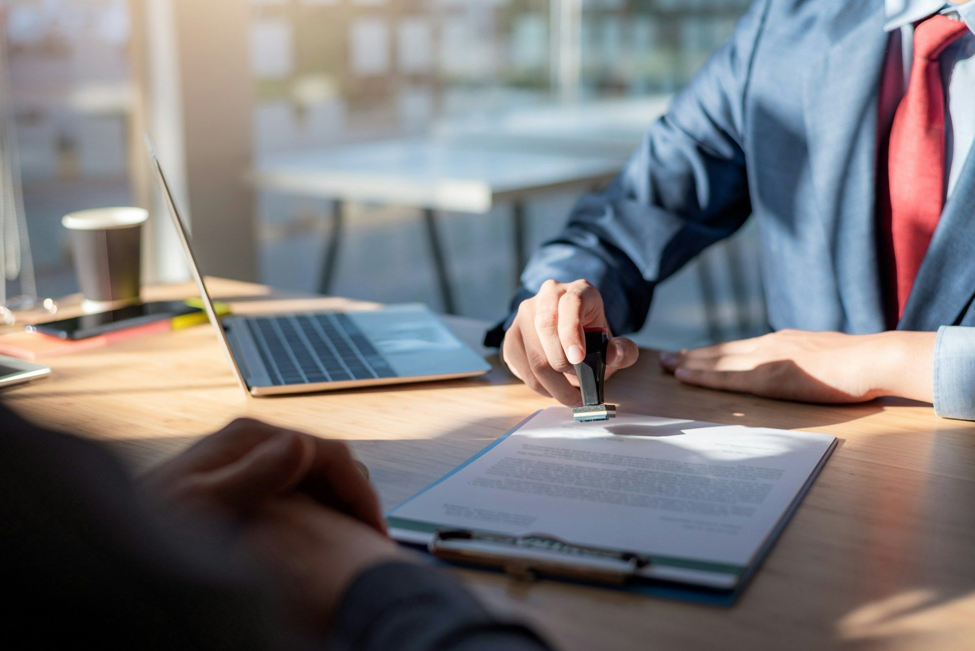 A man in a suit and tie is sitting at a table signing a document.