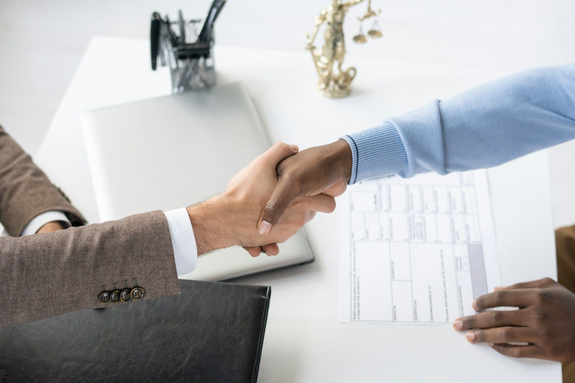 A man and a woman are shaking hands over a table.