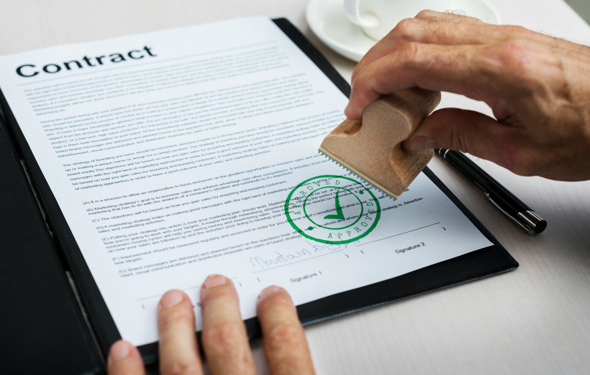 A person is stamping a contract on a clipboard.