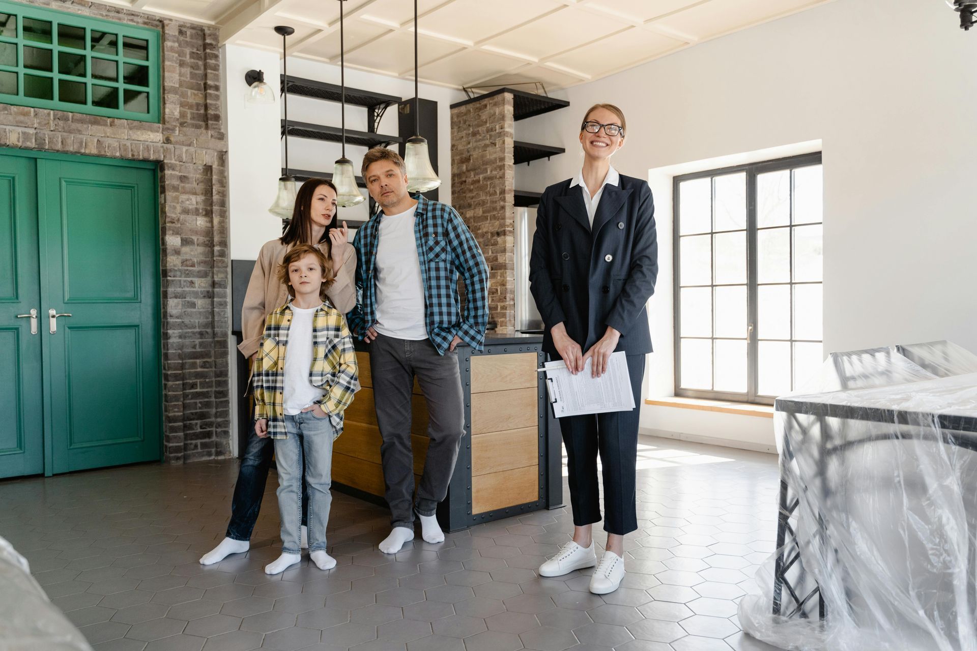 Real estate agent with a family viewing a home's interior, smiling.
