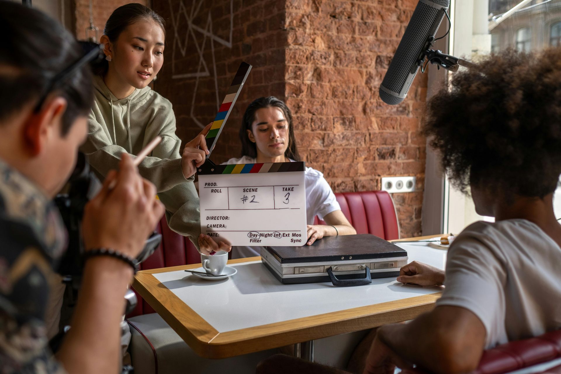 A group of people are sitting at a table with a microphone and a clapper board.