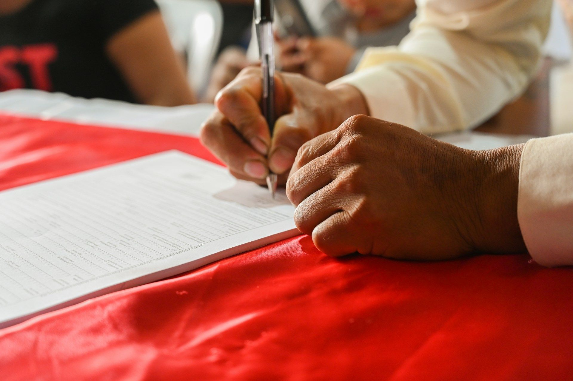 A man is writing on a piece of paper with a pen.
