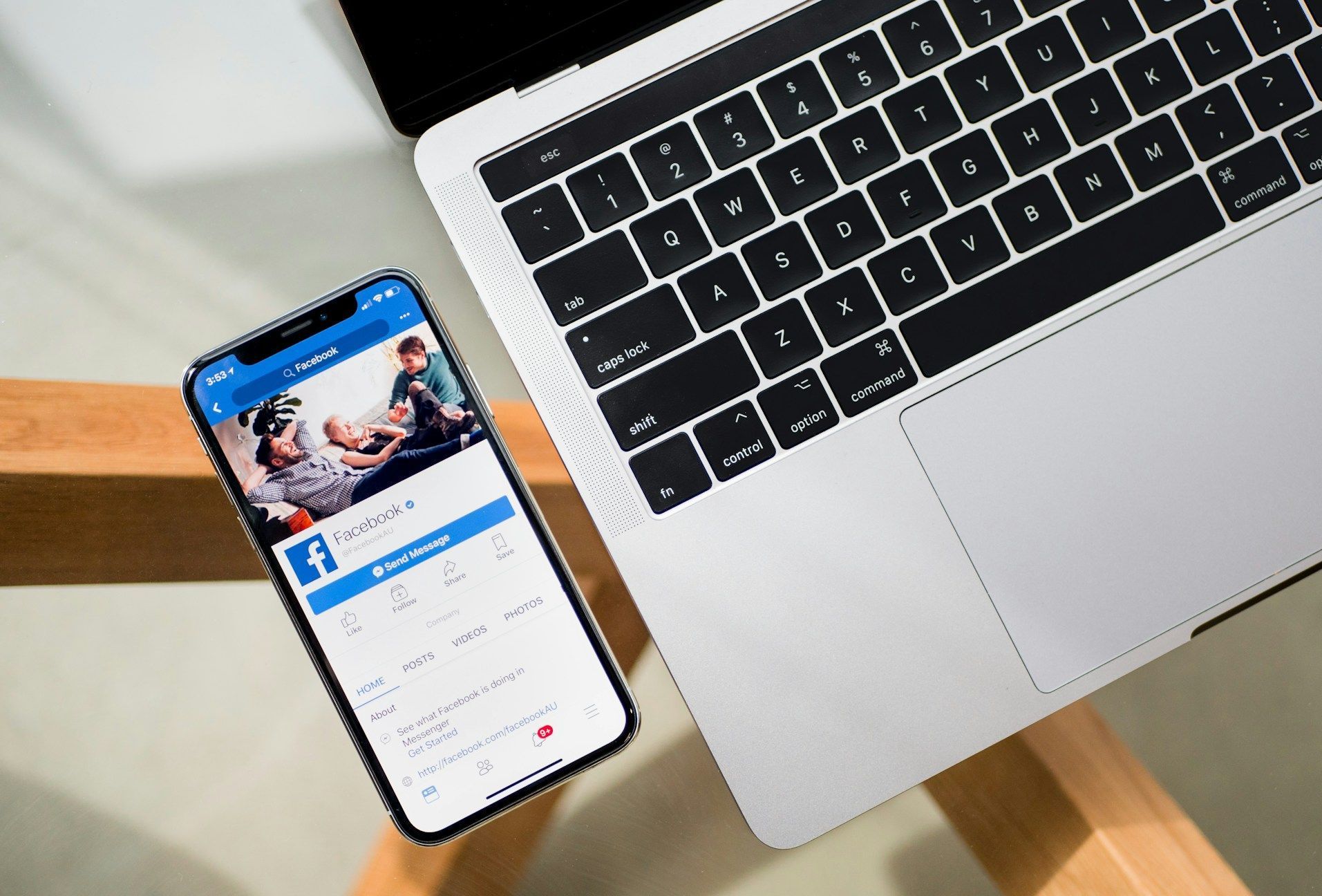 A phone with a facebook app open next to a laptop