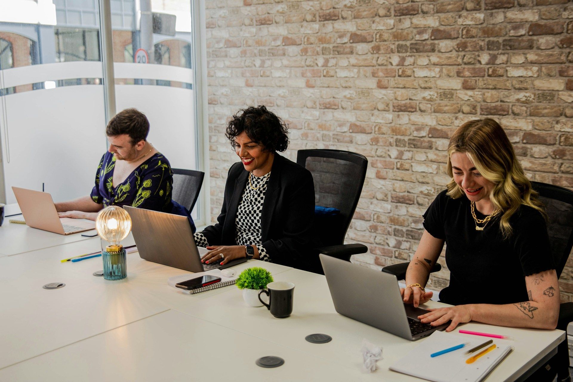 Three people are sitting at a table with laptops.