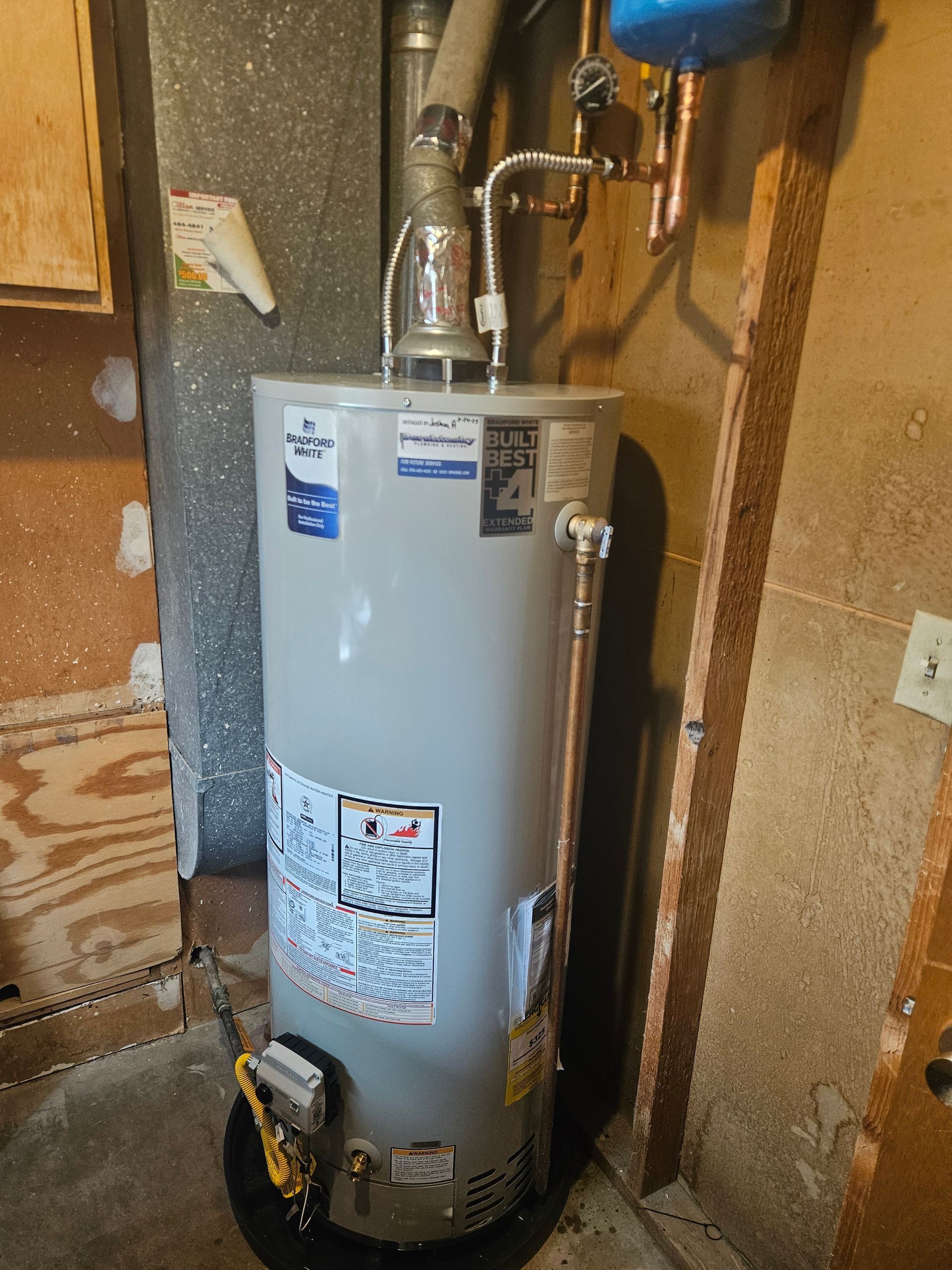 A water heater is sitting in a basement next to a wall.