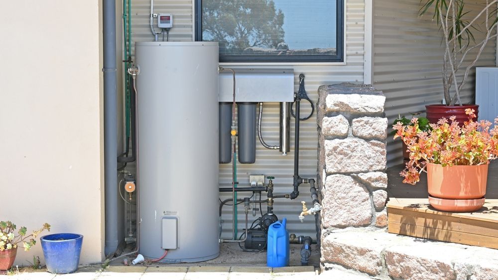 Two water heaters are hanging on a wall next to copper pipes.