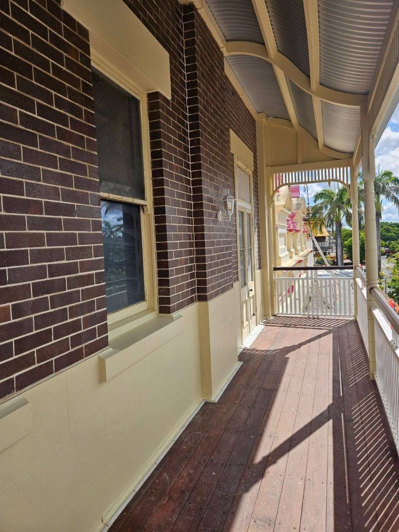 A Long Hallway Between Two Brick Buildings With a Wooden Floor — Chops Painting in Coral Cove, QLD