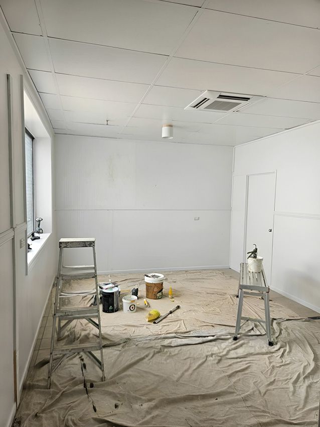 An Empty Room With a Ladder and Buckets of Paint on the Floor — Chops Painting in Coral Cove, QLD