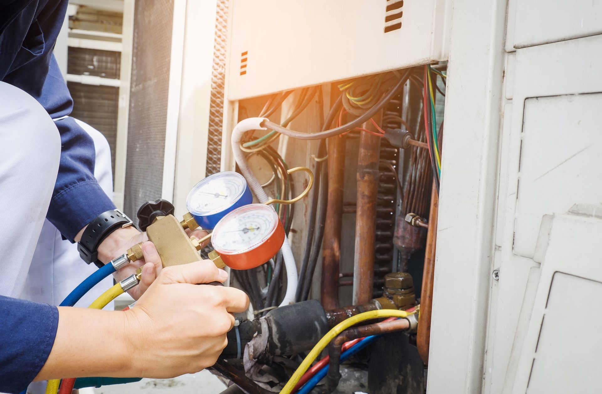A man is working on a boiler in a bathroom.