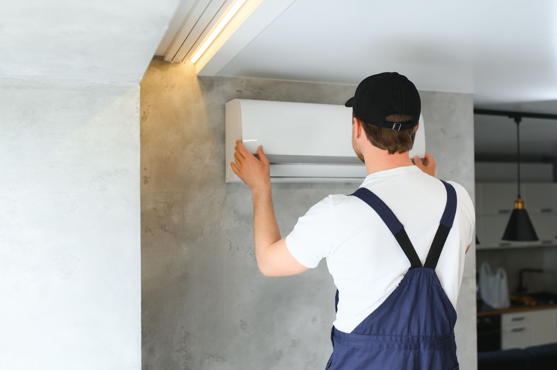 A man is installing an air conditioner on a wall.