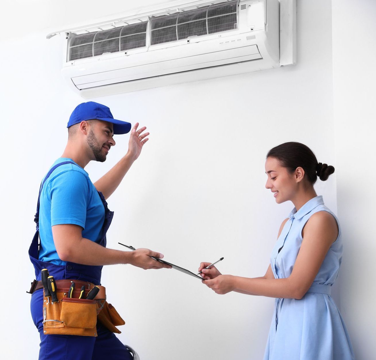 A man is talking to a woman in front of an air conditioner.