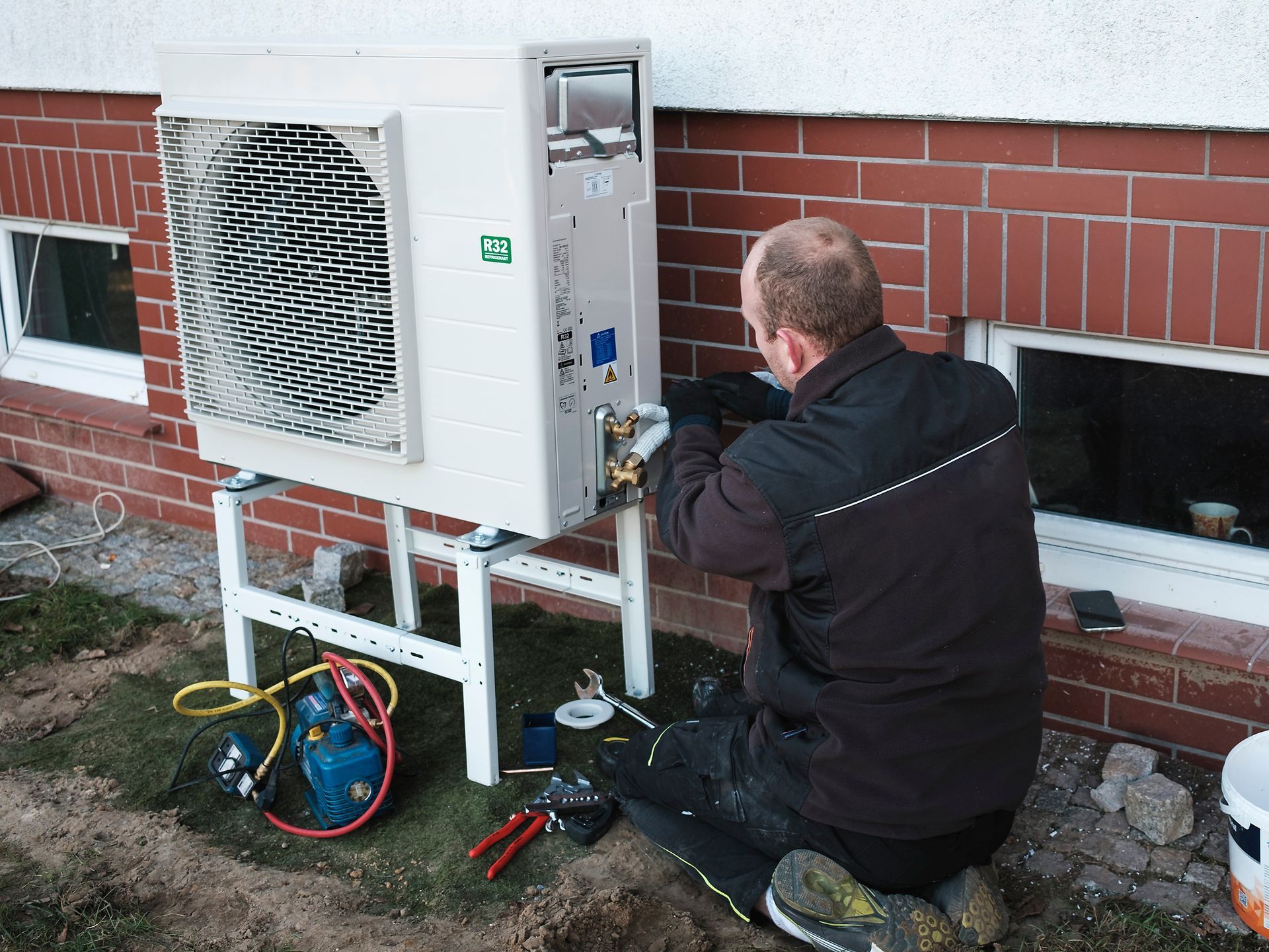 A man is working on a boiler in a bathroom.