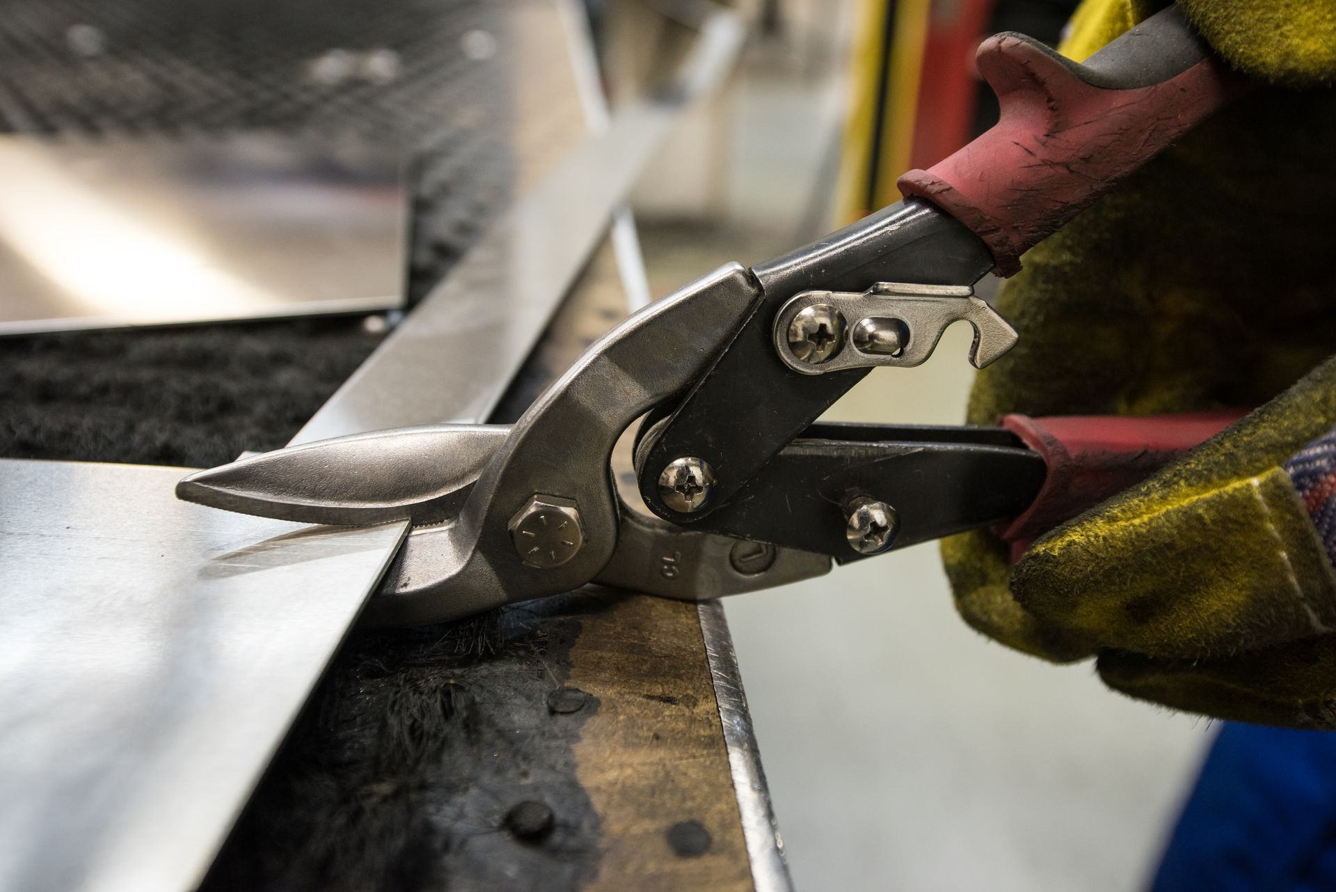 A person is cutting a piece of metal with scissors.