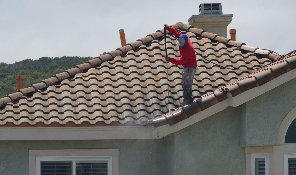 a man is cleaning the roof of a house with a high pressure washer