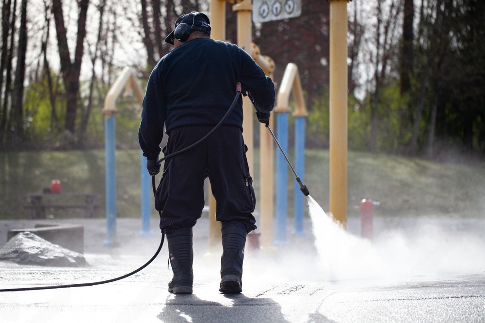 a man is using a high pressure washer to clean a playground .