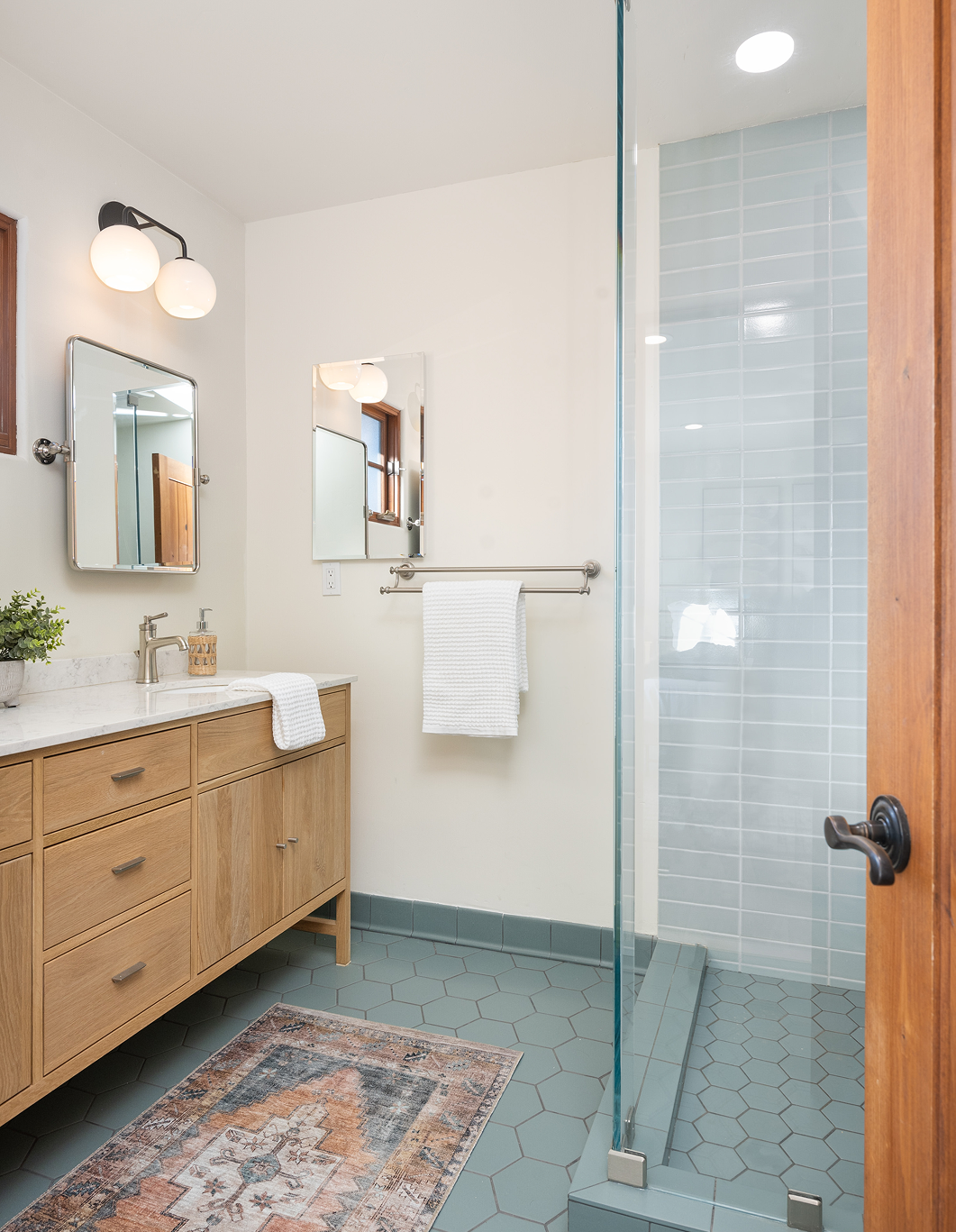 A bathroom with a sink , mirror , and walk in shower.