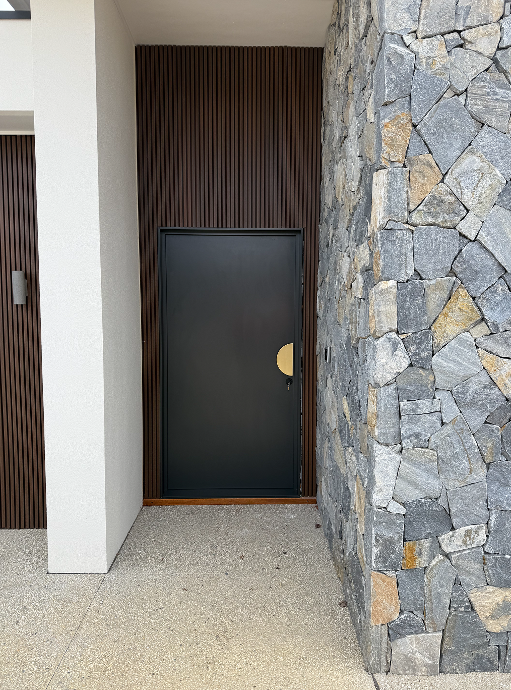 A black door is surrounded by a stone wall.