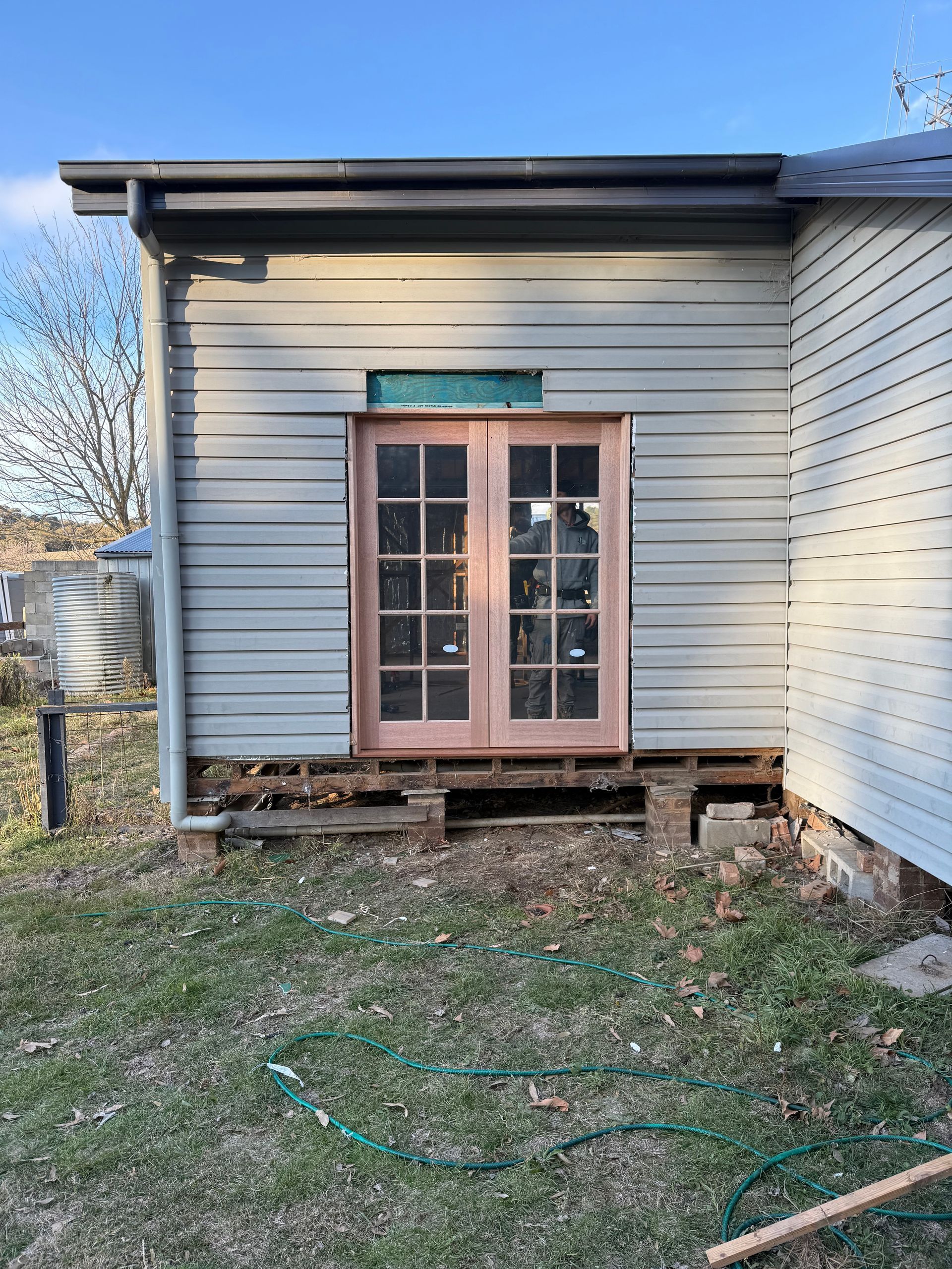 A white house with a pink door and a hose in front of it.