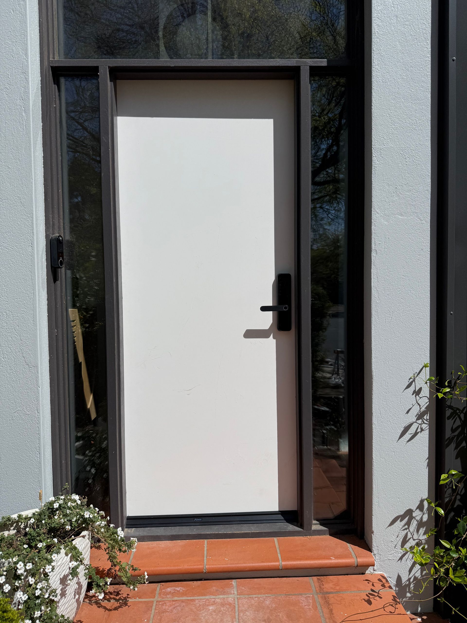A white door with a black handle is on the side of a building.
