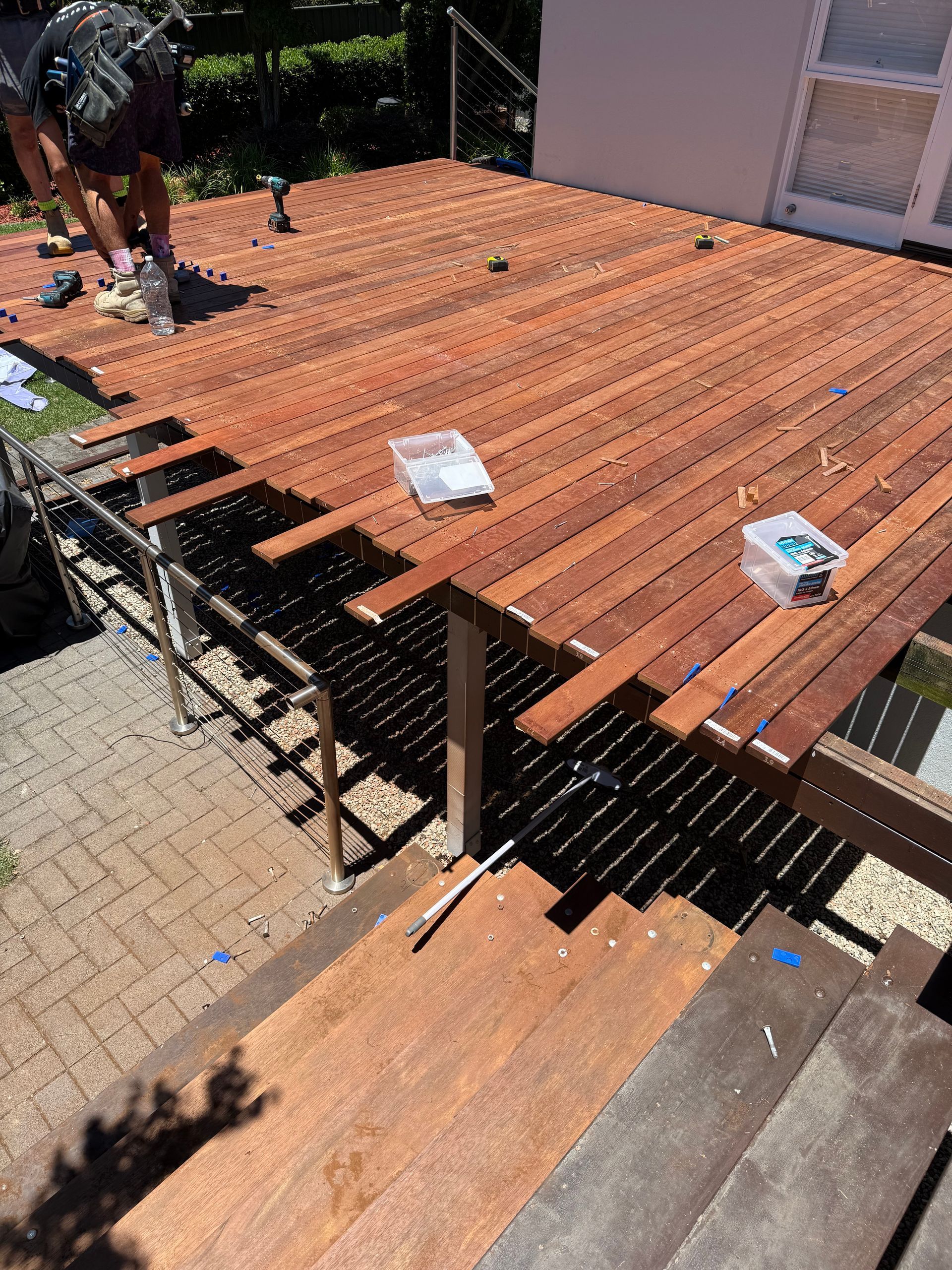 An aerial view of a house with a large deck with tables and chairs.